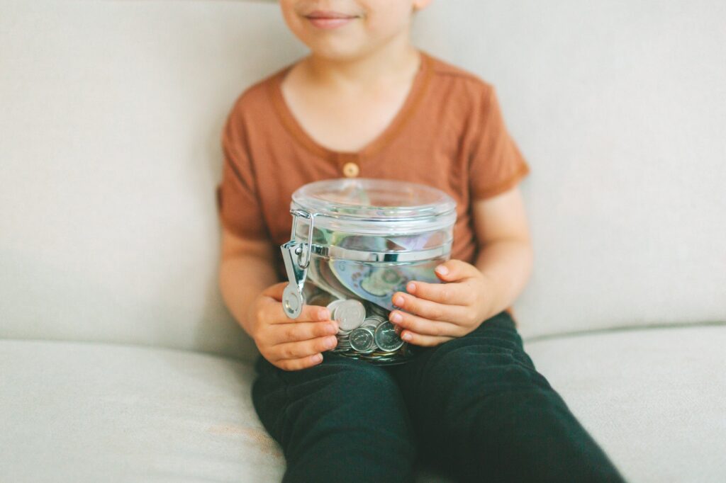 A child holding a jar of money.