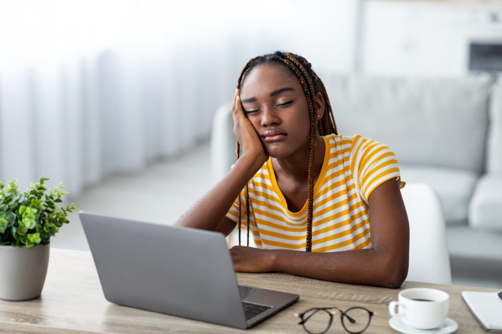 Exhausted african american woman freelancer sleeping in front of laptop