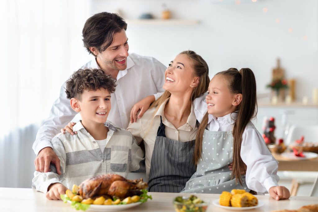 Happy family with parents and kids posing together in kitchen, preparing meal for Christmas or